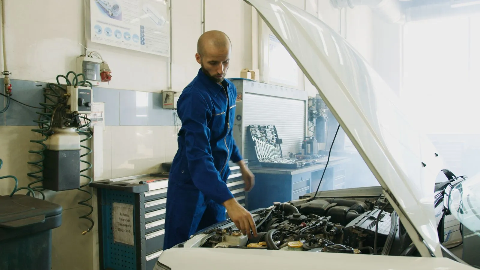 Kfz-Mechaniker prüft den Motorraum bei der Inspektion